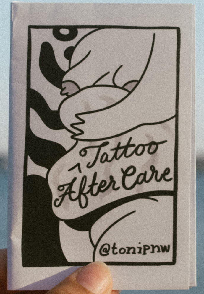Untitled A photo of a zine cover depicting a drawing of a fat, nude body. Underneath a stomach roll "Tattoo Aftercare" is written. This zine is titled "Tattoo Aftercare"