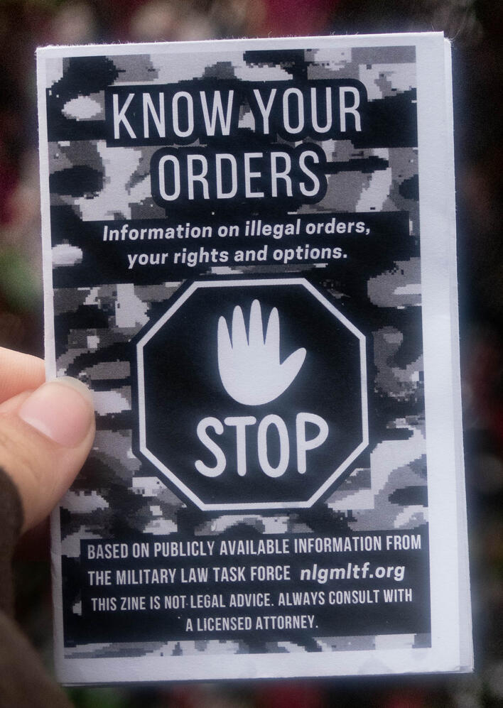 A photo of a zine cover depicting a stop sign on a camo background. This zine is titled "Know Your Orders"